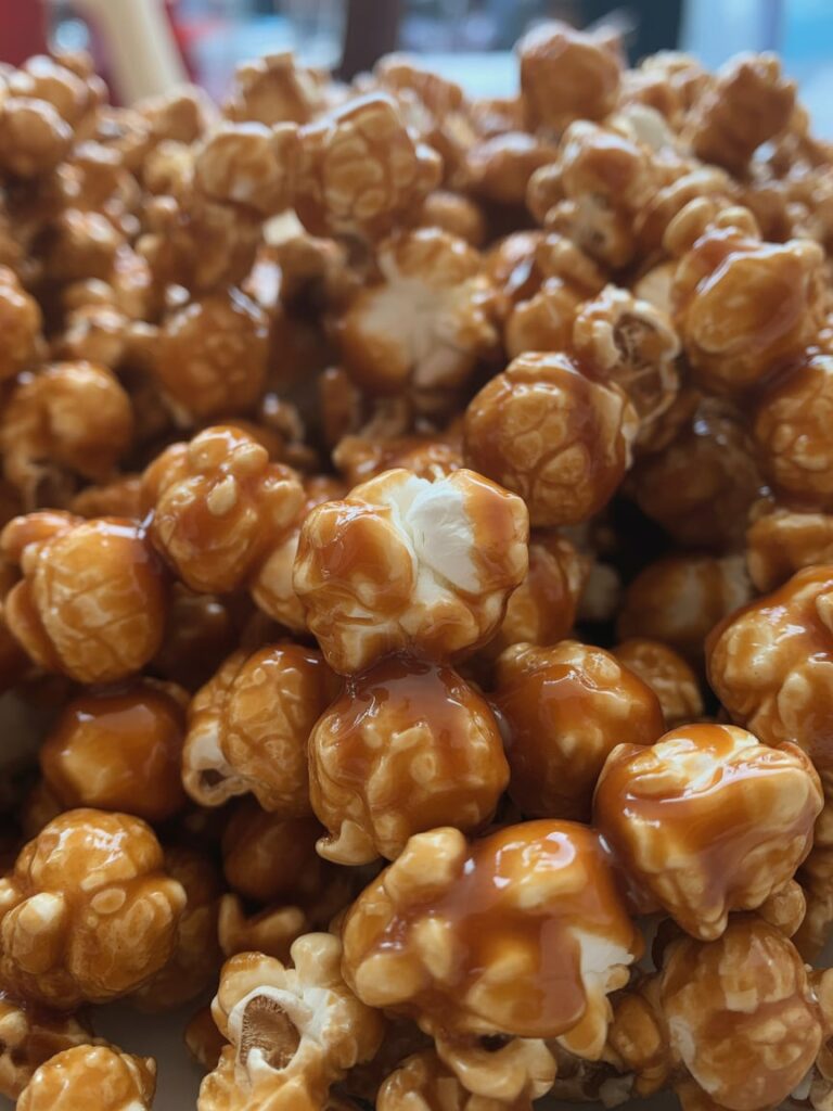 Close-up of golden caramel popcorn coated in glossy caramel glaze, showing rich texture and shine, perfect for a holiday snack or movie night treat.