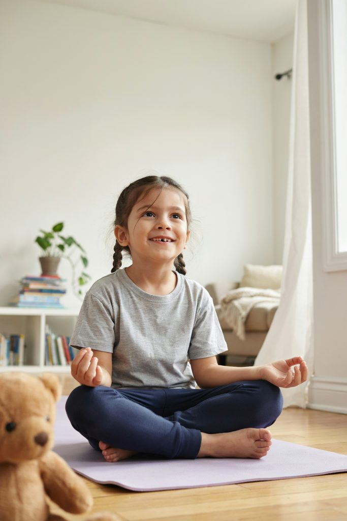Preschool-age child in a simple yoga pose, smiling