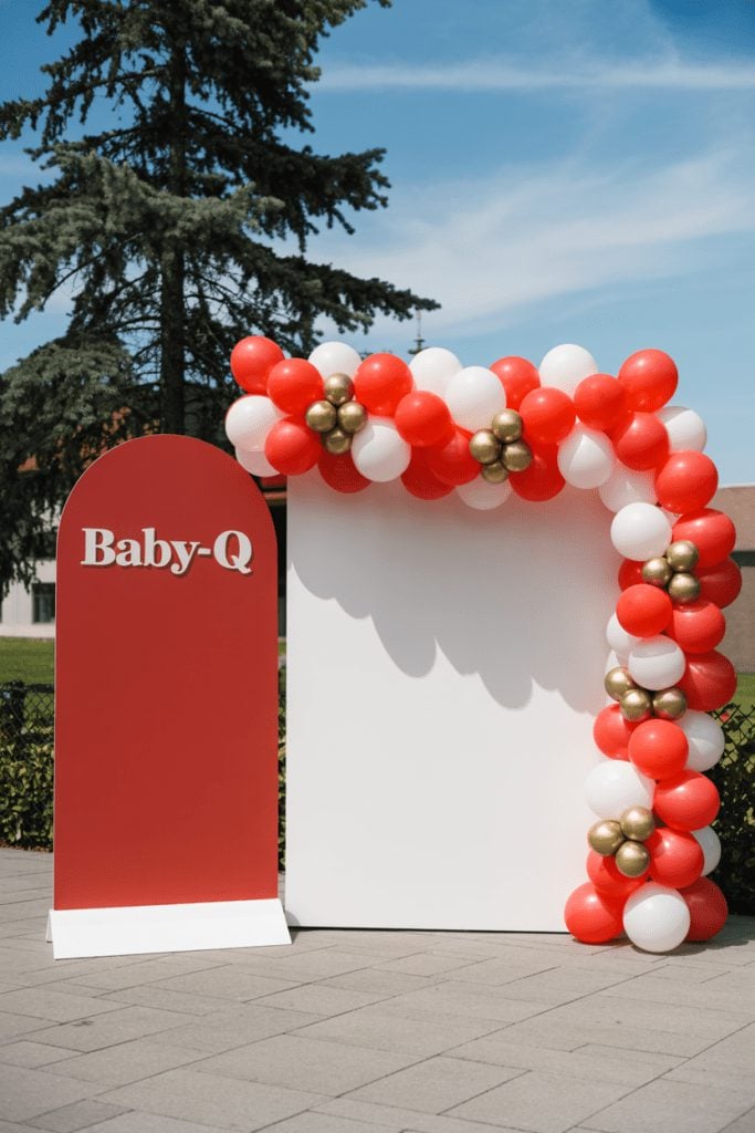 Bold red statement sign with red, white, and metallic balloon garland backdrop