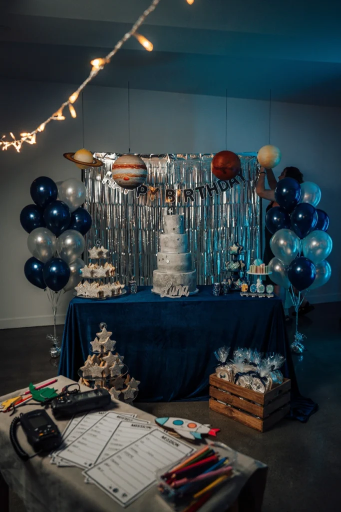 A darkened room decorated with foil space decorations and string-light stars for an astronaut birthday party