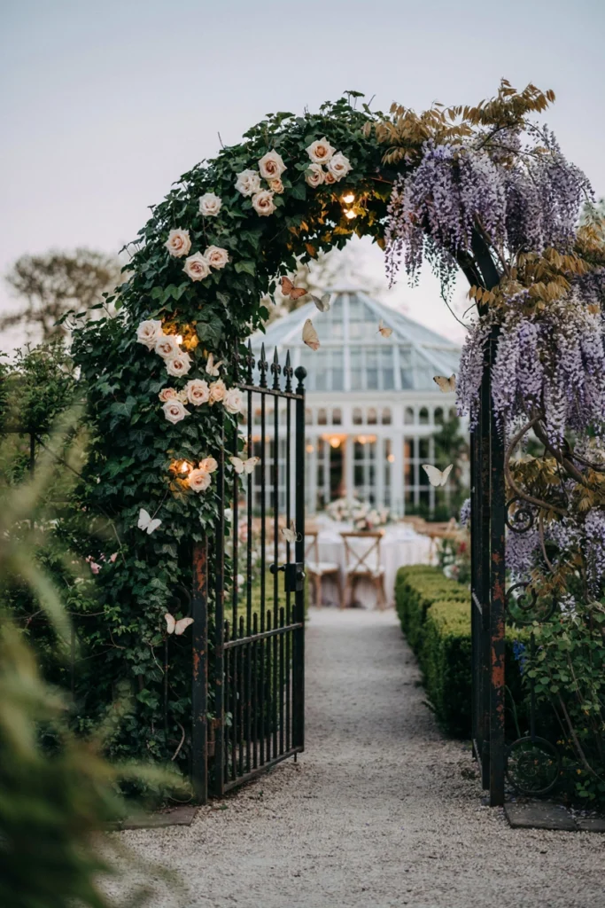 Freestanding vintage garden gate wrapped in climbing florals as a party entrance