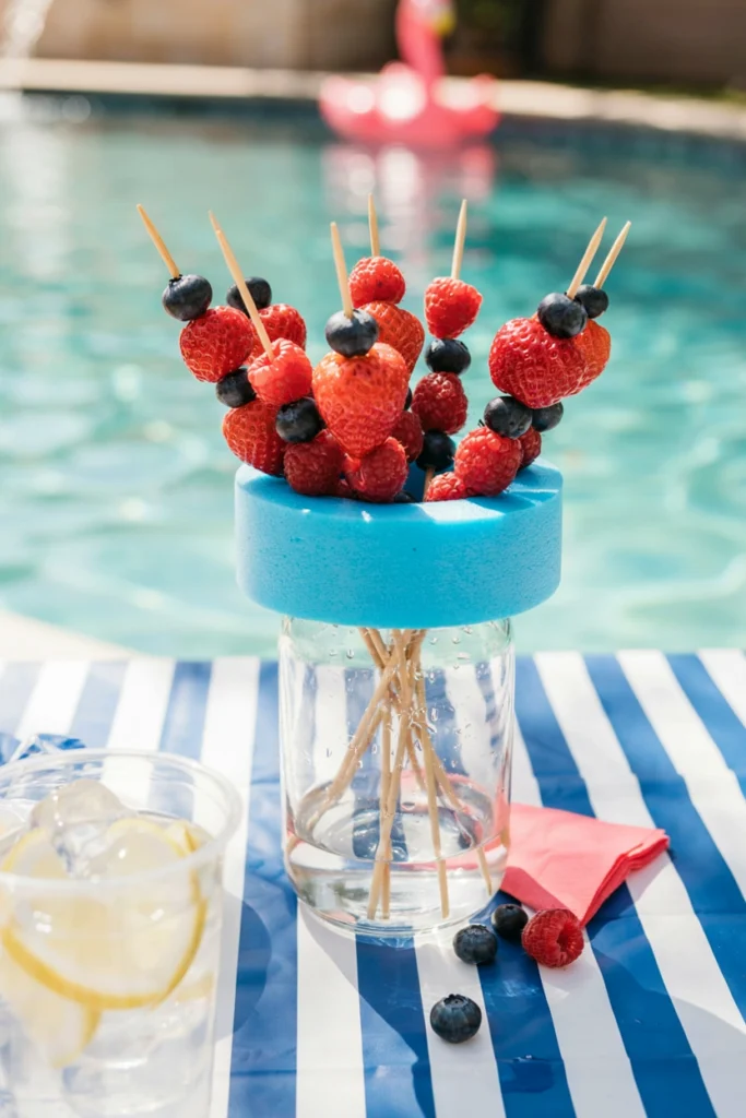 Wooden skewers threaded with strawberries, blueberries, and raspberries standing in a mason jar