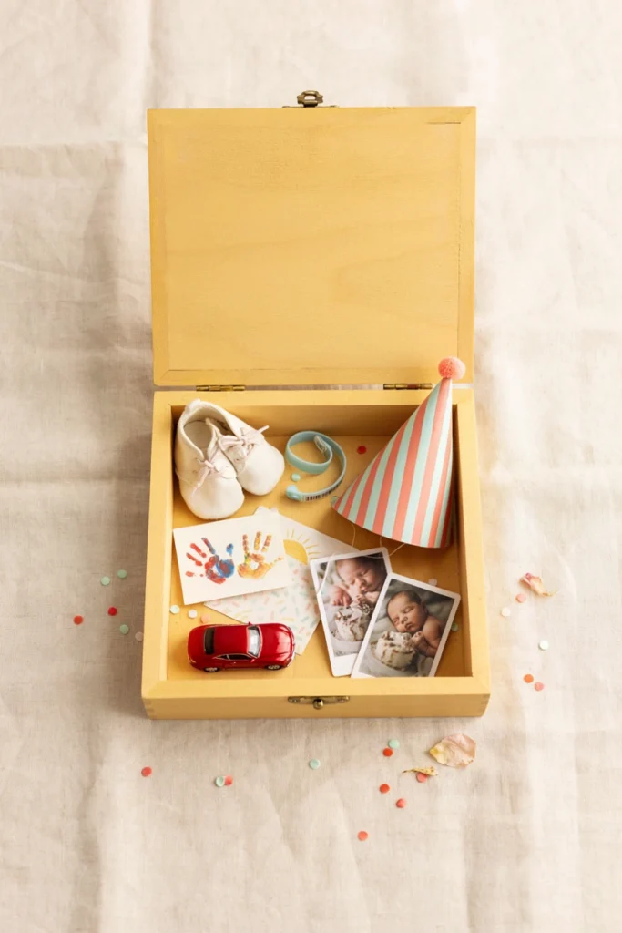 Open wooden memory box holding a hospital bracelet, a tiny sock, and a folded keepsake note
