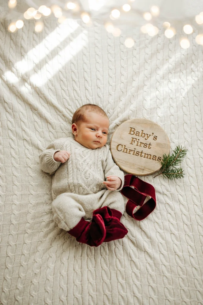 Baby beside rustic wooden Baby's First Christmas sign
