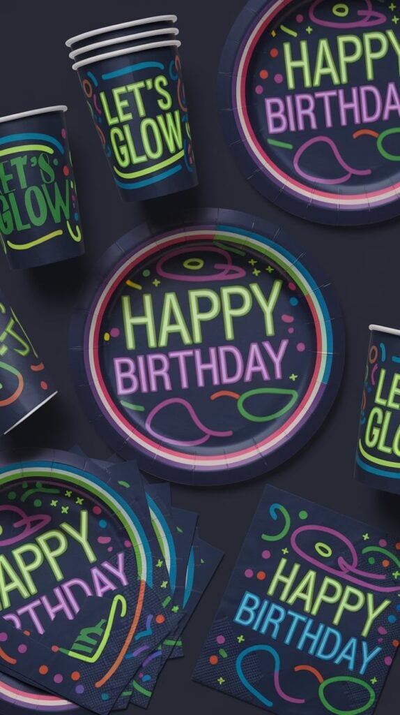 Neon Happy Birthday paper plates, cups, and napkins reading 'Let's Glow' on a dark background