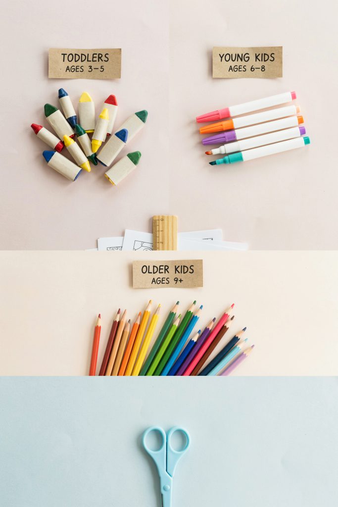 A flat-lay showing different coloring supply options arranged by age group—jumbo crayons for toddlers, markers for younger kids, colored pencils for older kids, neatly organized.
