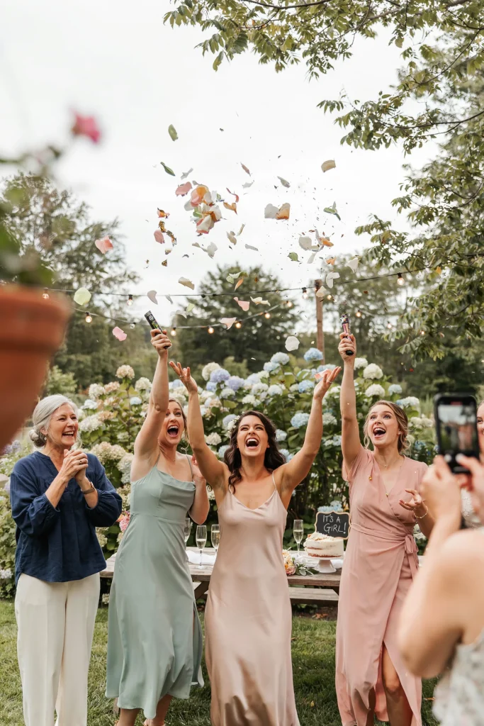 Guests holding confetti poppers mid-celebration, confetti exploding in mid-air. Joyful expressions. Bright, energetic moment. The shower's grand finale captured.