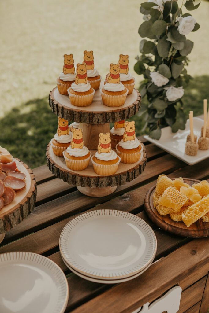 Classic Winnie the Pooh baby shower dessert table with honey jars and greenery