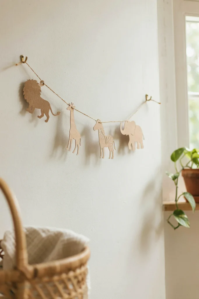 A string of paper animal silhouettes (lion, giraffe, zebra, elephant) suspended between two points with fishing line or twine.