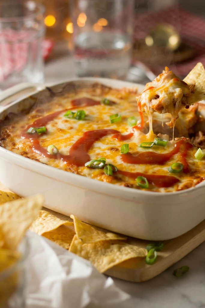 Baked buffalo chicken dip in a casserole dish with a tortilla chip scooping it