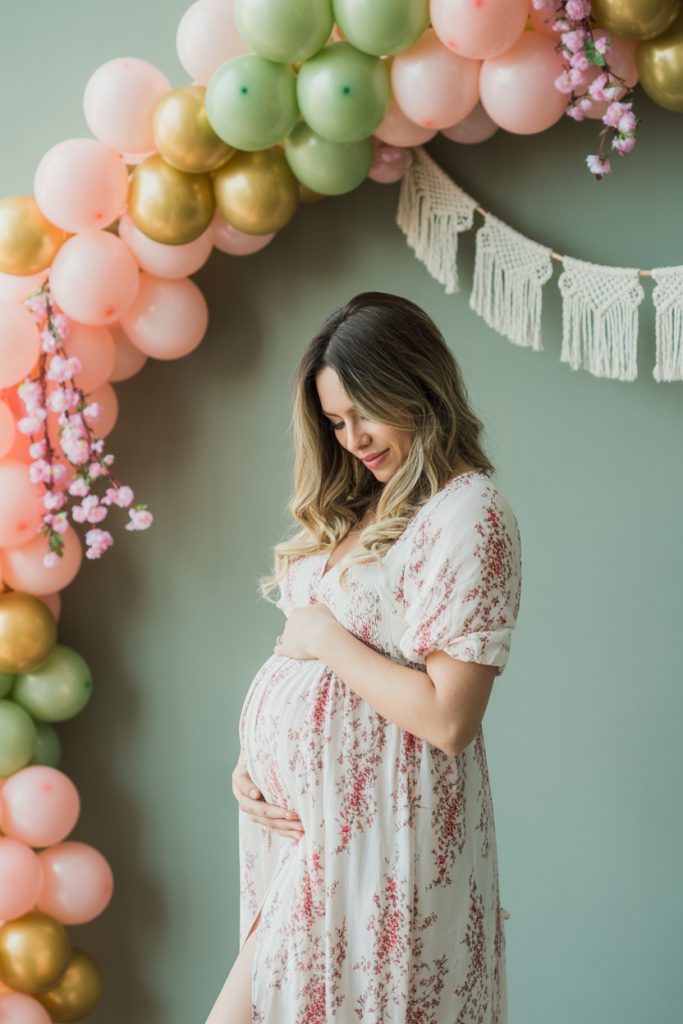 Pregnant mother under baby shower balloon arch