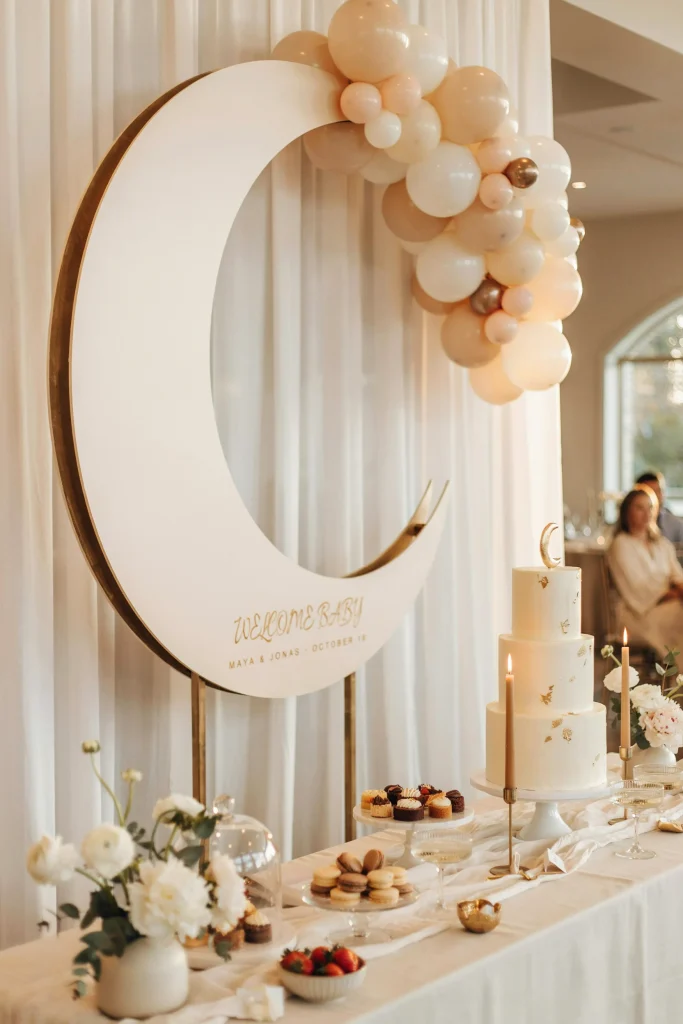Cream and gold over the moon baby shower dessert table with crescent moon backdrop