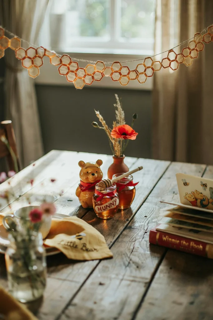 Red and yellow Winnie the Pooh baby shower dessert table with hunny pot favors