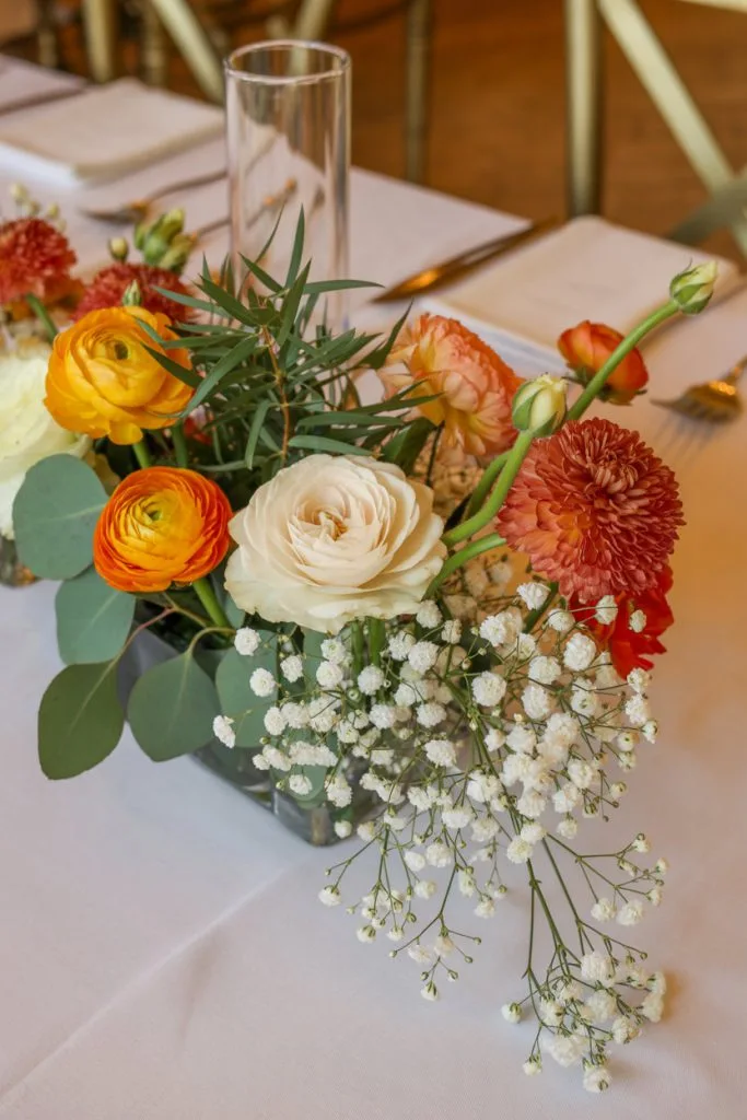 Vibrant orange and yellow floral centerpiece for fall baby shower