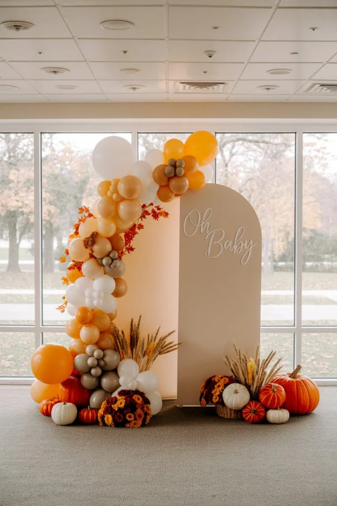 Elegant fall baby shower arch with pumpkin clusters and pampas grass