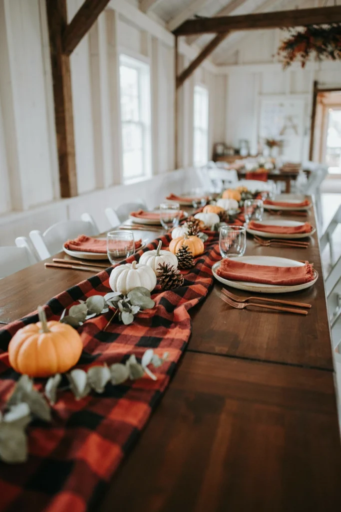 A red and black buffalo plaid table runner topped with small white pumpkins and pinecones