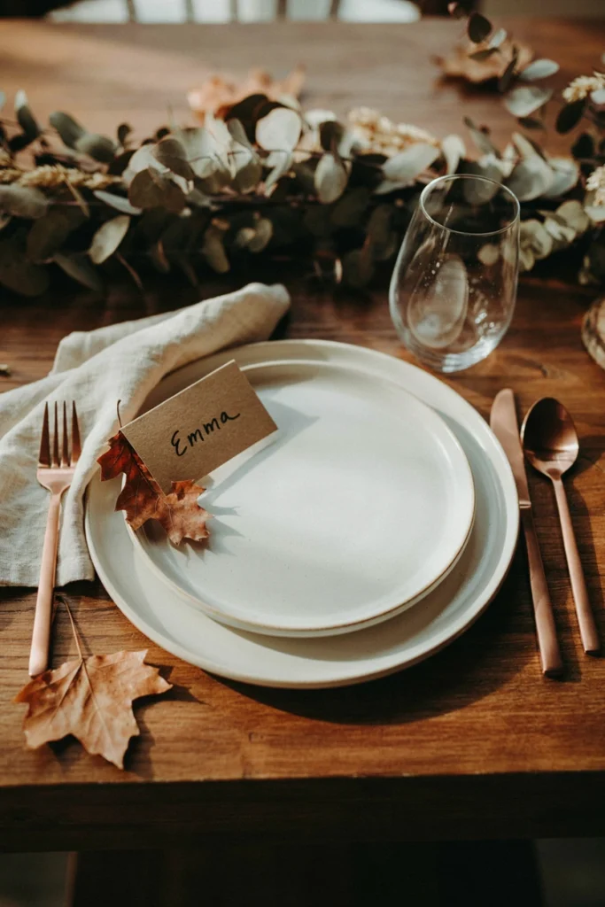 Simple kraft paper place cards with a single pressed autumn leaf glued to the corner of each name