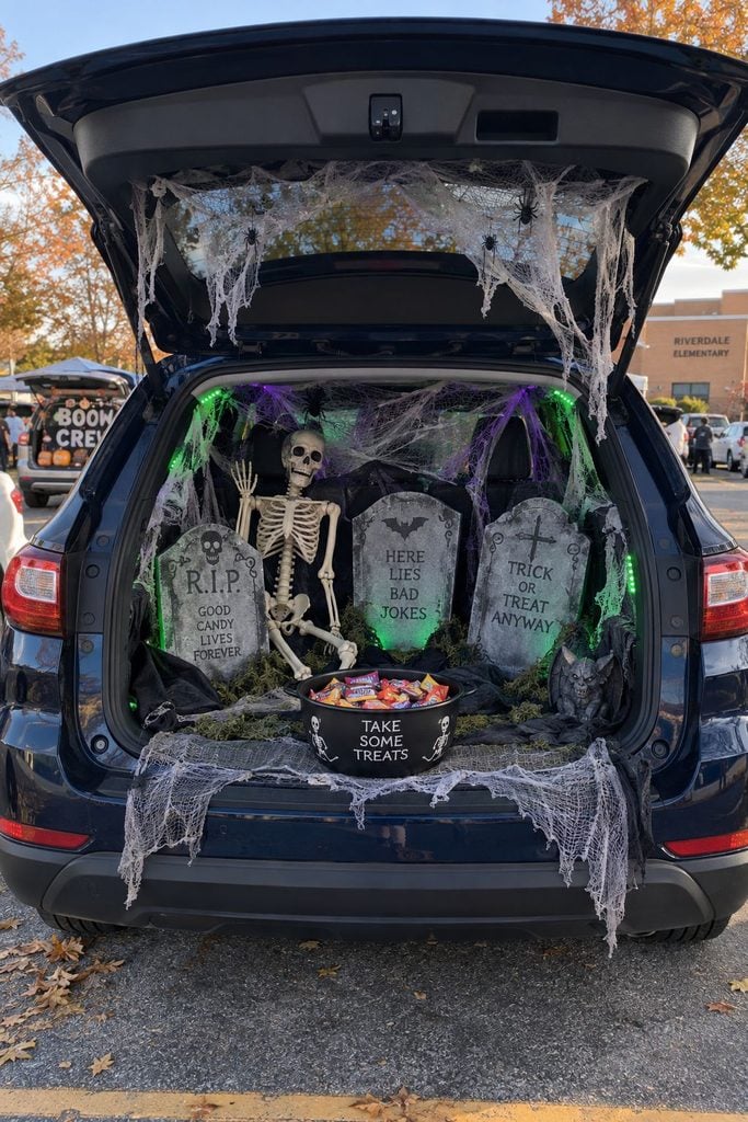 Trunk or treat car set up as a spooky graveyard with foam tombstones, skeletons, and cobwebs