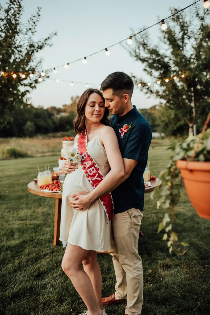 Mom-to-be wearing a strawberry-print sash next to a partner in a matching corsage