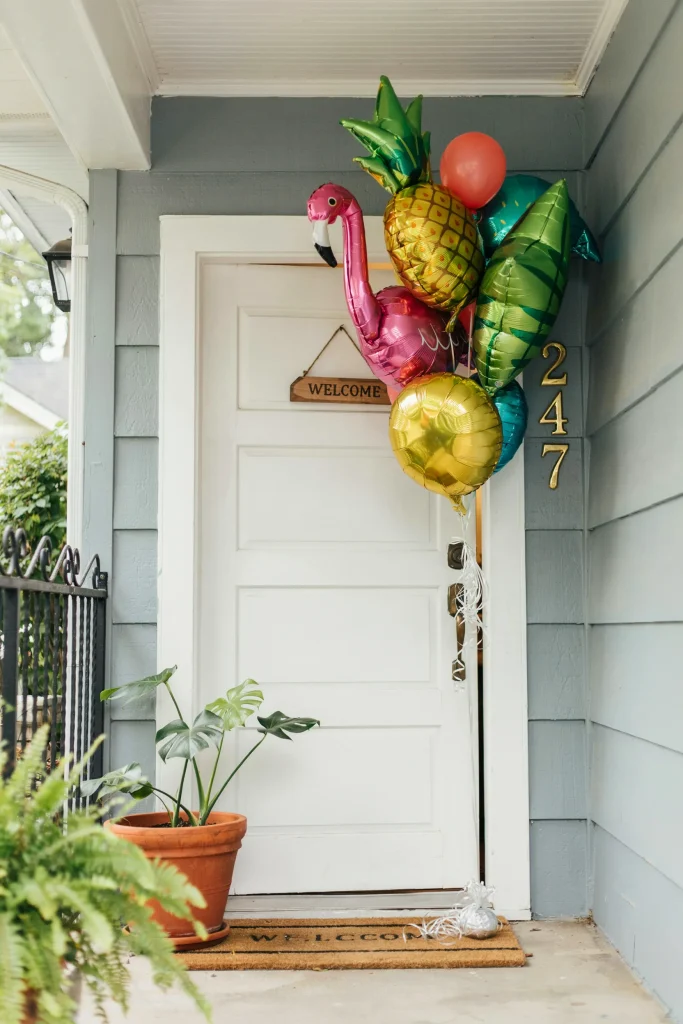 A cluster of foil tropical balloons framing a front door or backyard gate