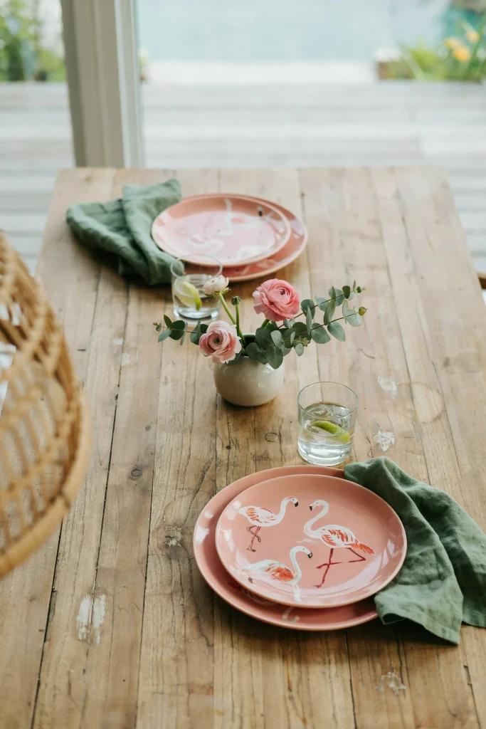 Hot pink plates paired with dark green napkins on a wood table, flamingo motif visible.