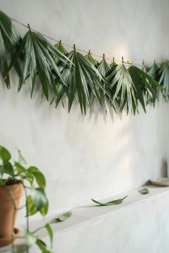 A wall or table edge strung with a lush green palm leaf garland, catching afternoon light.