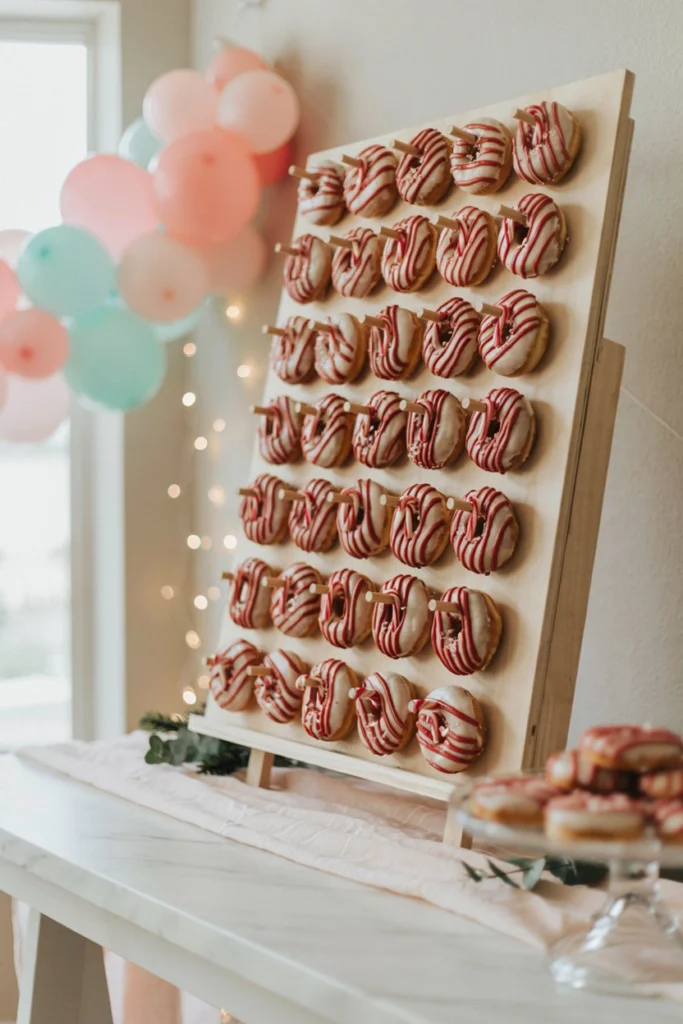 Candy cane striped donut wall with mini candy canes hooked between rows for a Christmas baby shower