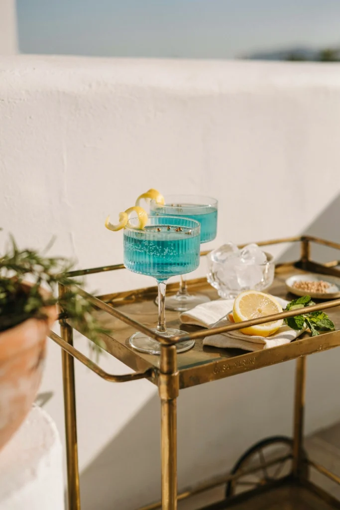 Tall glasses of bright turquoise sparkling mocktail garnished with a lemon twist and edible pearls