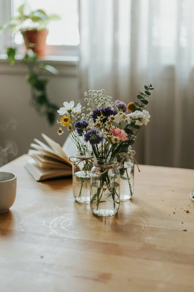 Mason jars filled with mixed dollar-store wildflowers tied simply with kitchen twine on an everyday kitchen table