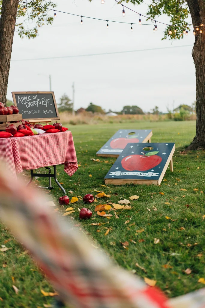 Apple-themed cornhole game station for a baby shower
