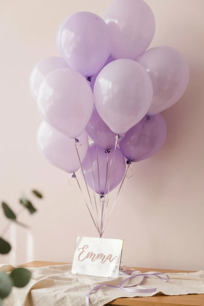 Dusty lavender balloon cluster with a custom acrylic baby name sign centerpiece topper