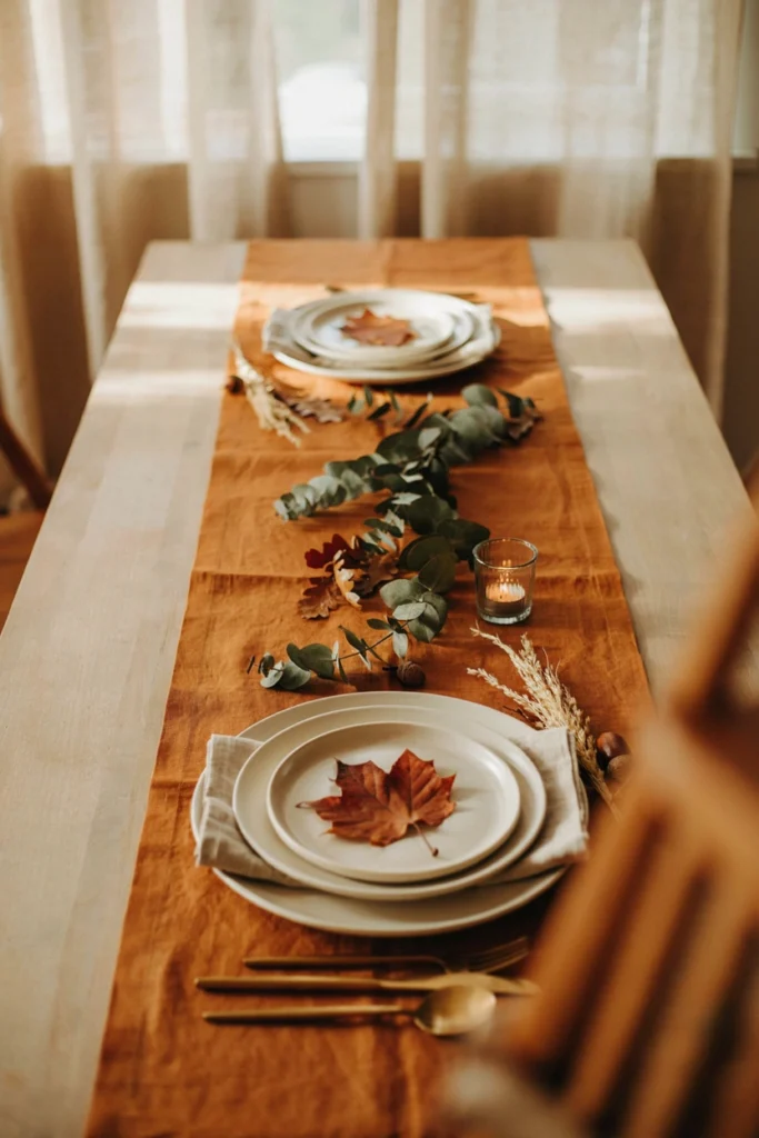 Minimalist amber and cream fall baby shower table with pressed maple leaves