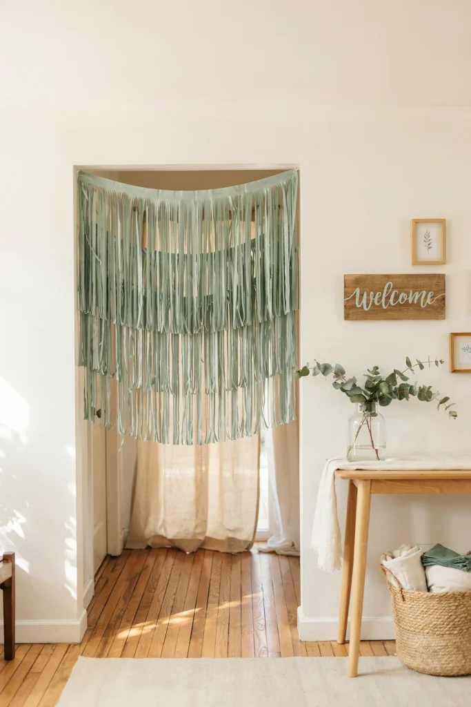 Sage green foil fringe backdrop curtains framing a doorway entrance at a baby shower