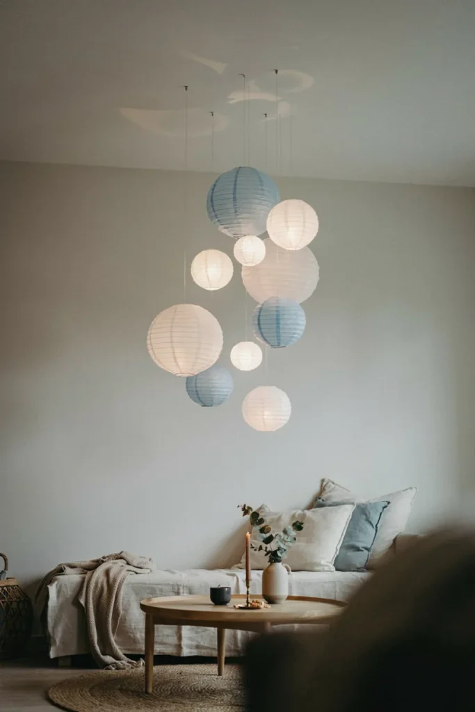 A cluster of round white and pale blue paper lanterns of varying sizes suspended at different heights above a seating area, resembling rising bubbles