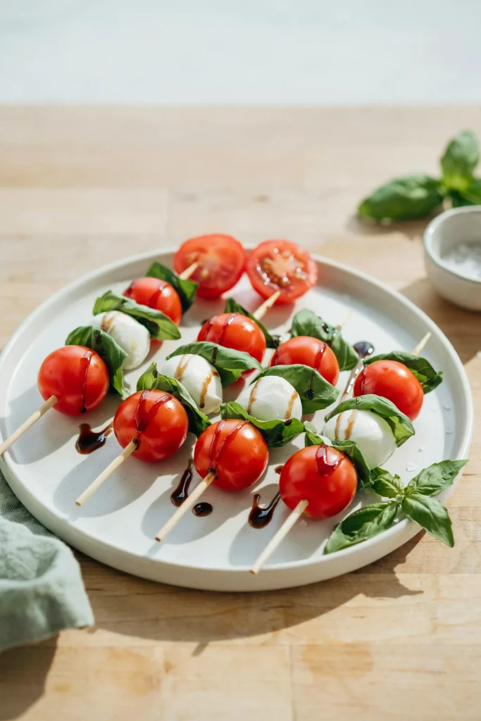 Caprese skewers with cherry tomatoes, basil, and mozzarella drizzled with balsamic glaze