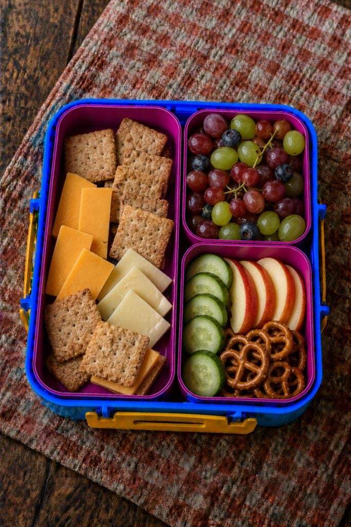 Sliced cheese and crackers beside grapes