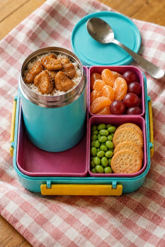 Glossy teriyaki chicken pieces over rice in a thermos
