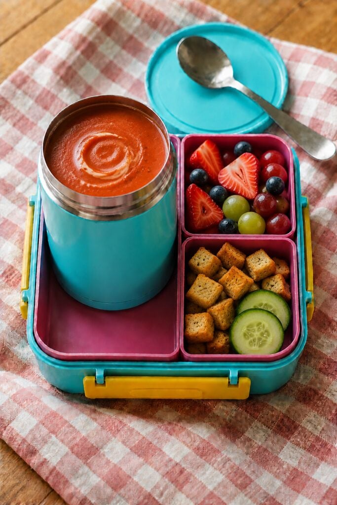 Smooth tomato soup topped with croutons in a thermos cup