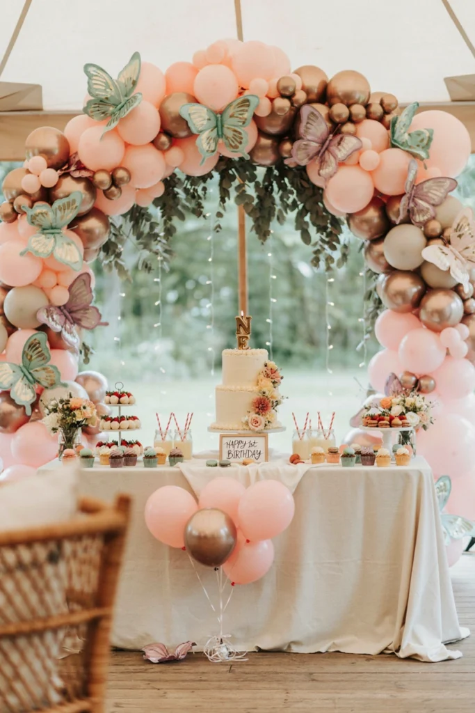 Whimsical pastel butterfly garden first birthday party with hanging paper butterflies over a floral dessert table