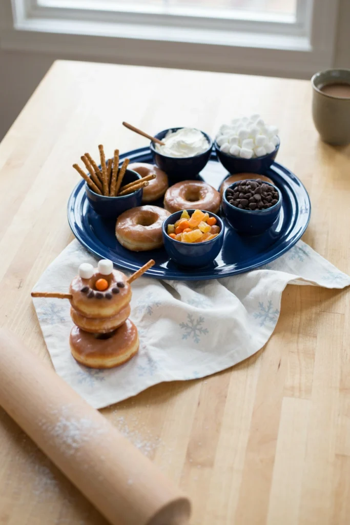 Glazed donuts with bowls of frosting and candy for decorating into snowmen