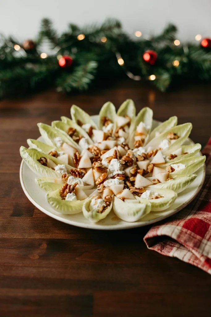 Belgian endive leaves filled with diced pear, goat cheese, and walnuts, arranged on a platter