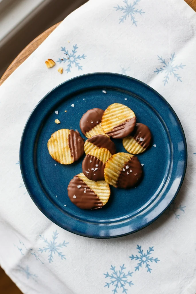 Ridged potato chips half-dipped in chocolate on parchment paper