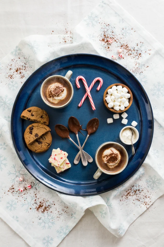 Wooden board with mugs of cocoa, marshmallows, cookies, and candy canes