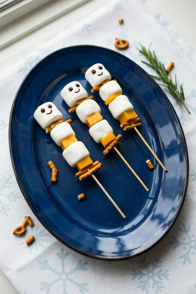 Skewers threaded with marshmallow snowmen, pretzel sticks, and cheese cubes