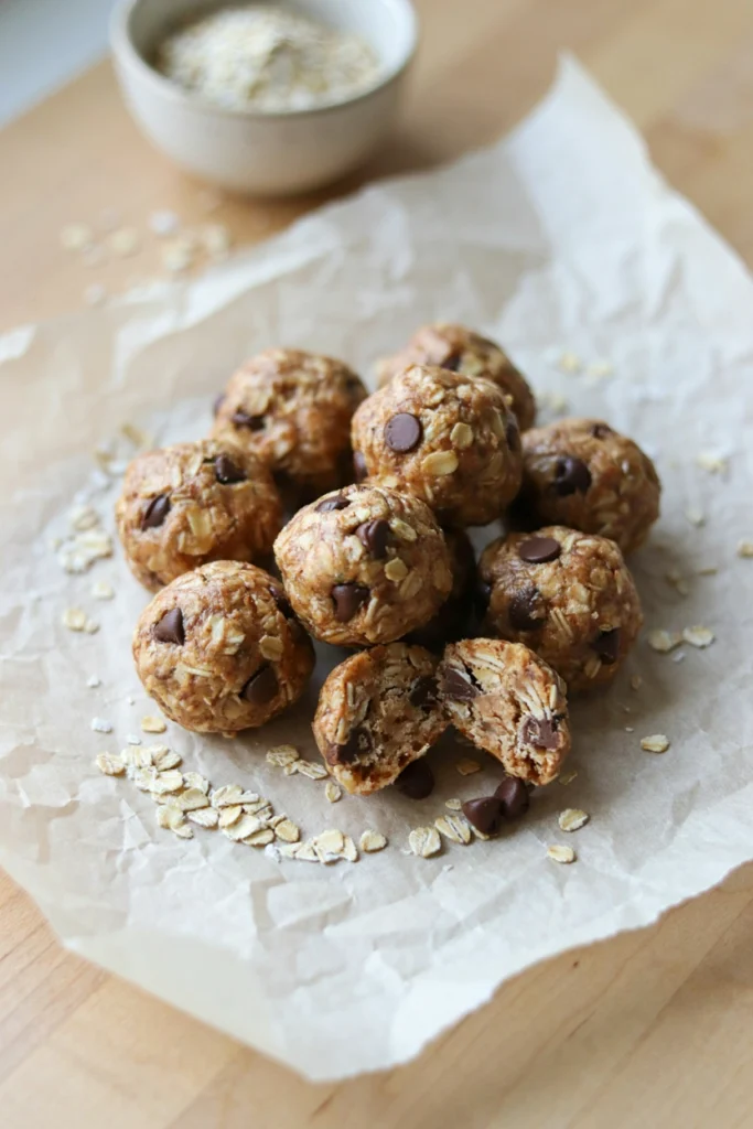 Peanut butter oat energy balls on a wooden board, one broken in half
