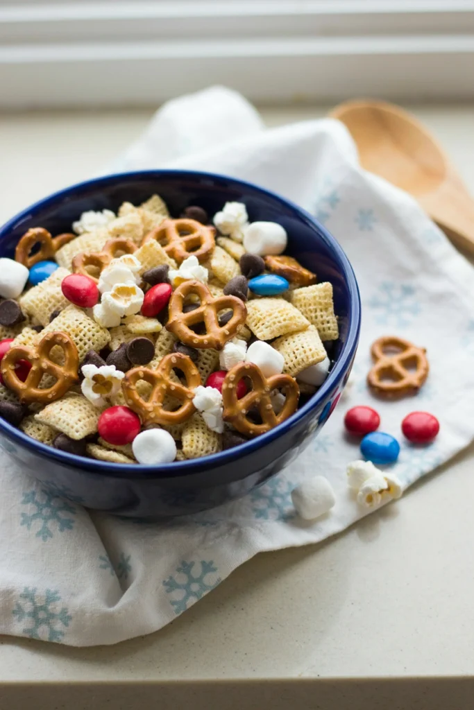 Bowl of colorful snack mix with pretzels, cereal, candy, and nuts