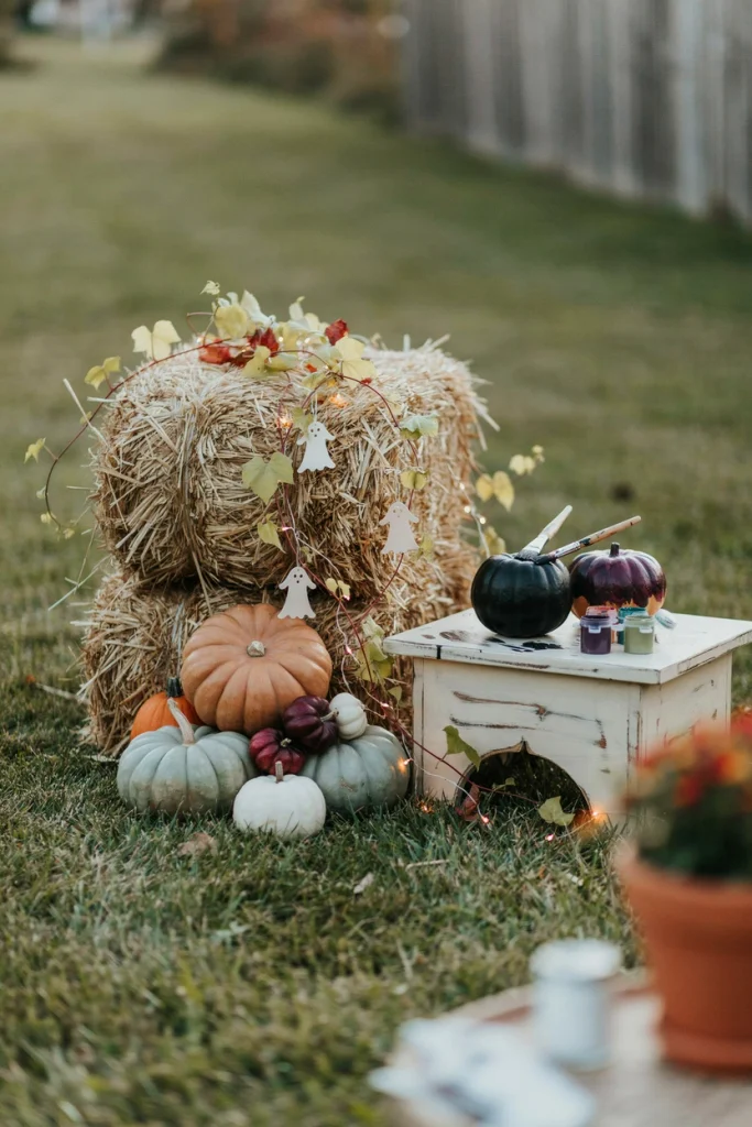 Kids painting pumpkins at a low pumpkin decorating station beside hay bales at a kids Halloween party