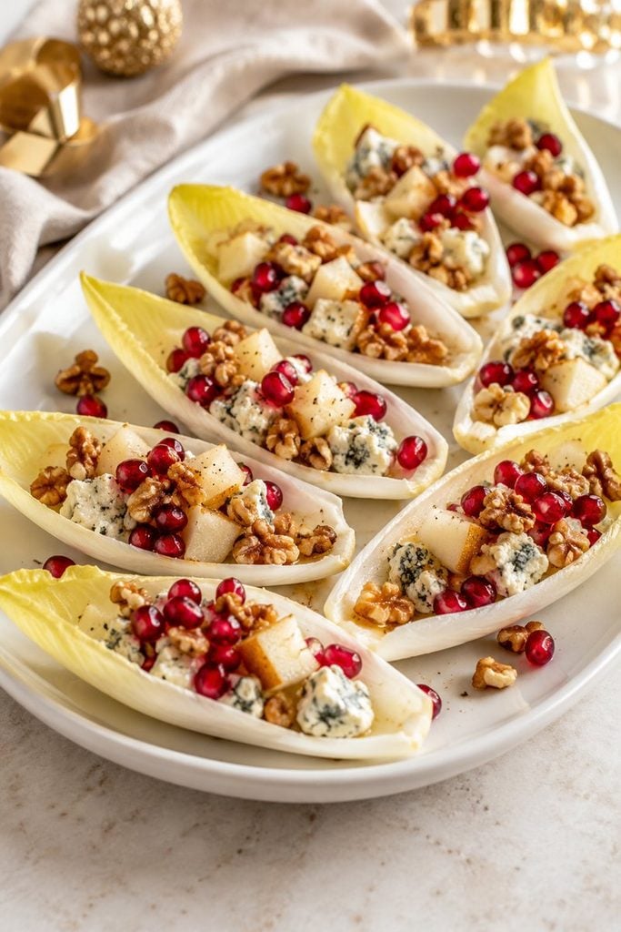 Endive leaf boats filled with blue cheese, walnuts, diced pear, and pomegranate seeds